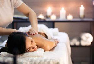 A woman receives a relaxing back massage in a spa with a soothing candlelit ambiance, promoting stress relief and muscle relaxation
