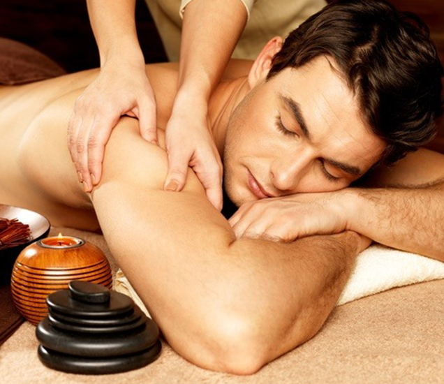 A man is peacefully enjoying a relaxing massage while lying on his stomach in a spa setting, embracing self-care for men